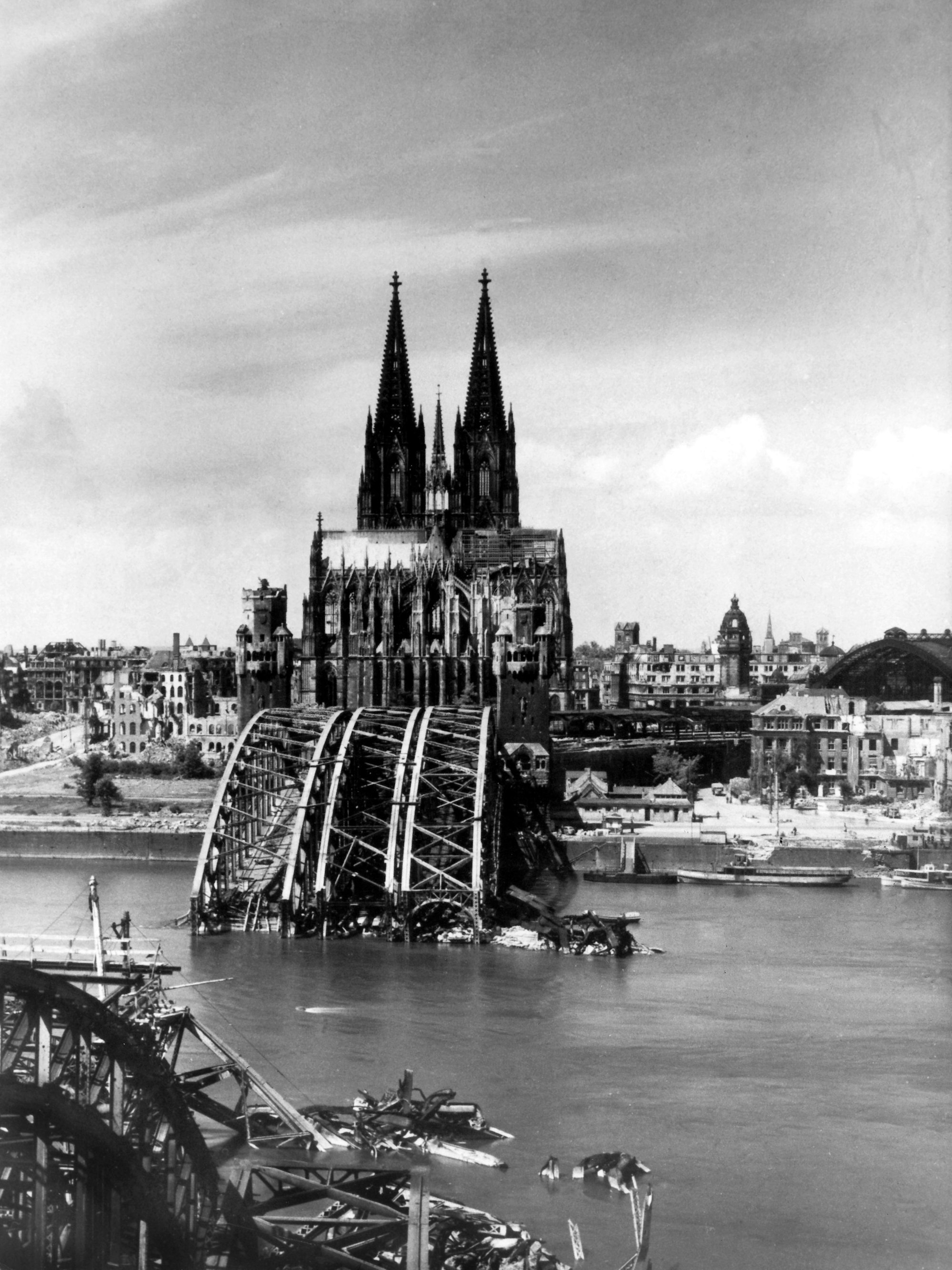 Die Aufnahme von 1945 zeigt den Blick auf den Kölner Dom, der als einziges Bauwerk aus den Trümmern der Stadt hervorragt. Vorn die zerstörte Hohenzollernbrücke.