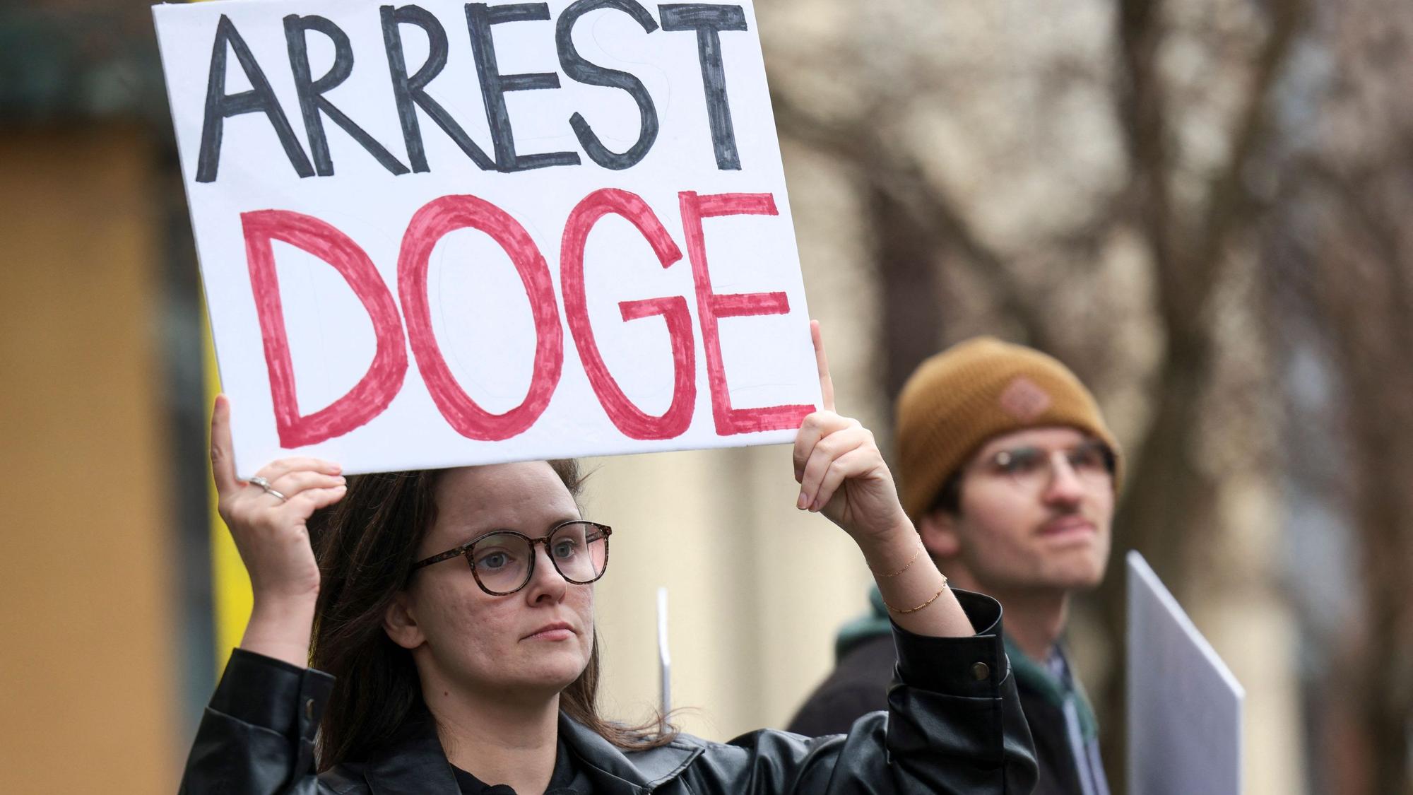Das Bild zeigt Protestierende Mitte Februar in Seattle. Sie richten sich gegen die neu gegründete Behörde ‚Department of Government Efficiency‘, kurz DOGE, der US-Milliardär Elon Musk vorsteht.