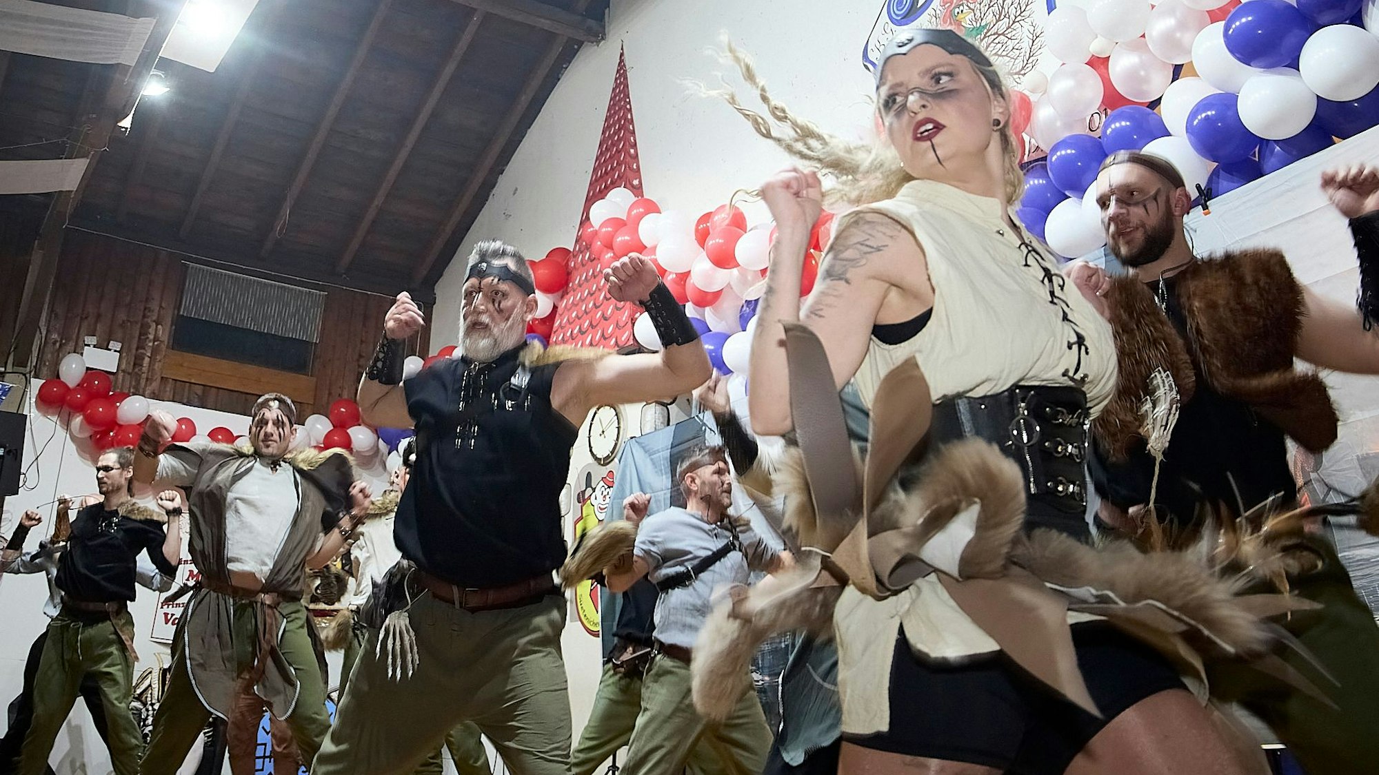 Eine Gruppe als Wikinger verkleidete Menschen tanzt auf einer Bühne.