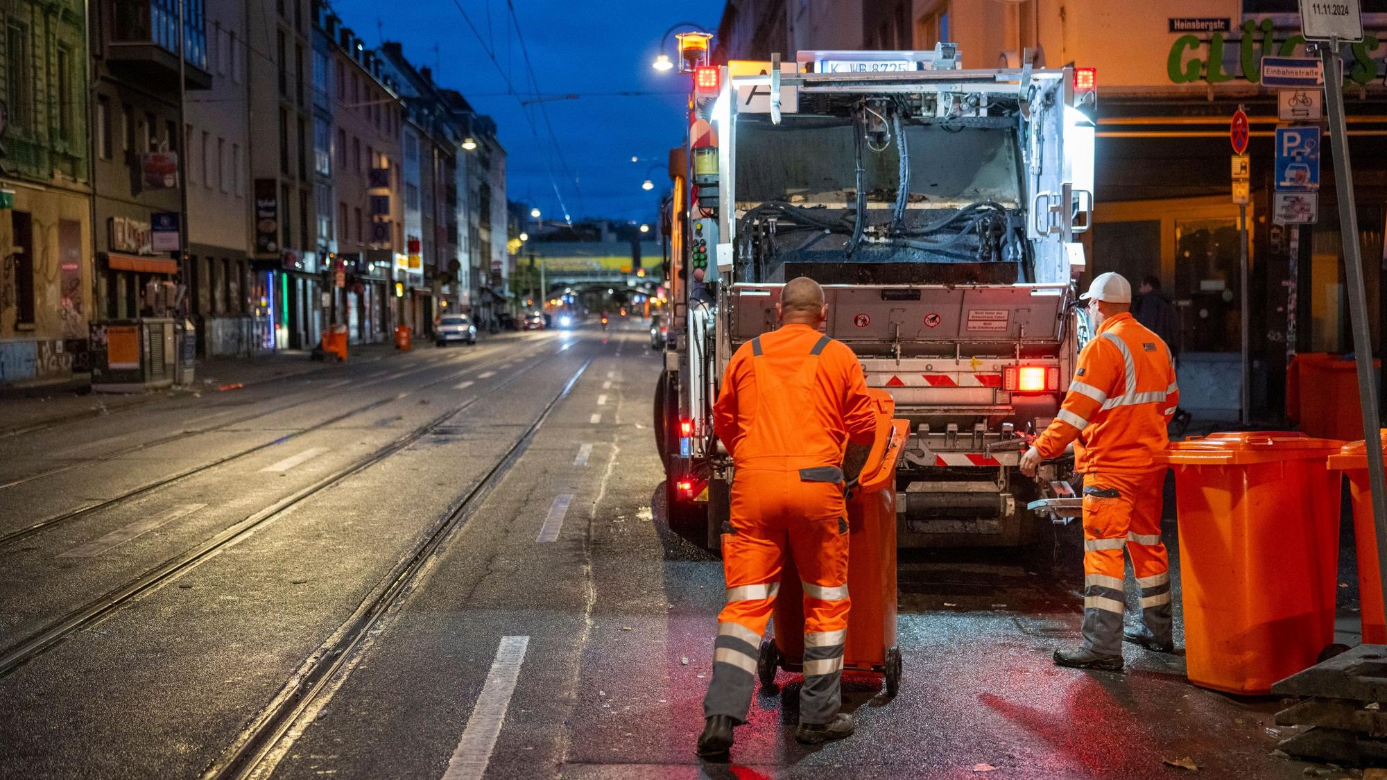 Mitarbeitende der AWB leeren nach dem „Elften im Elften“ Mülltonnen, die an der Zülpicher Straße stehen.