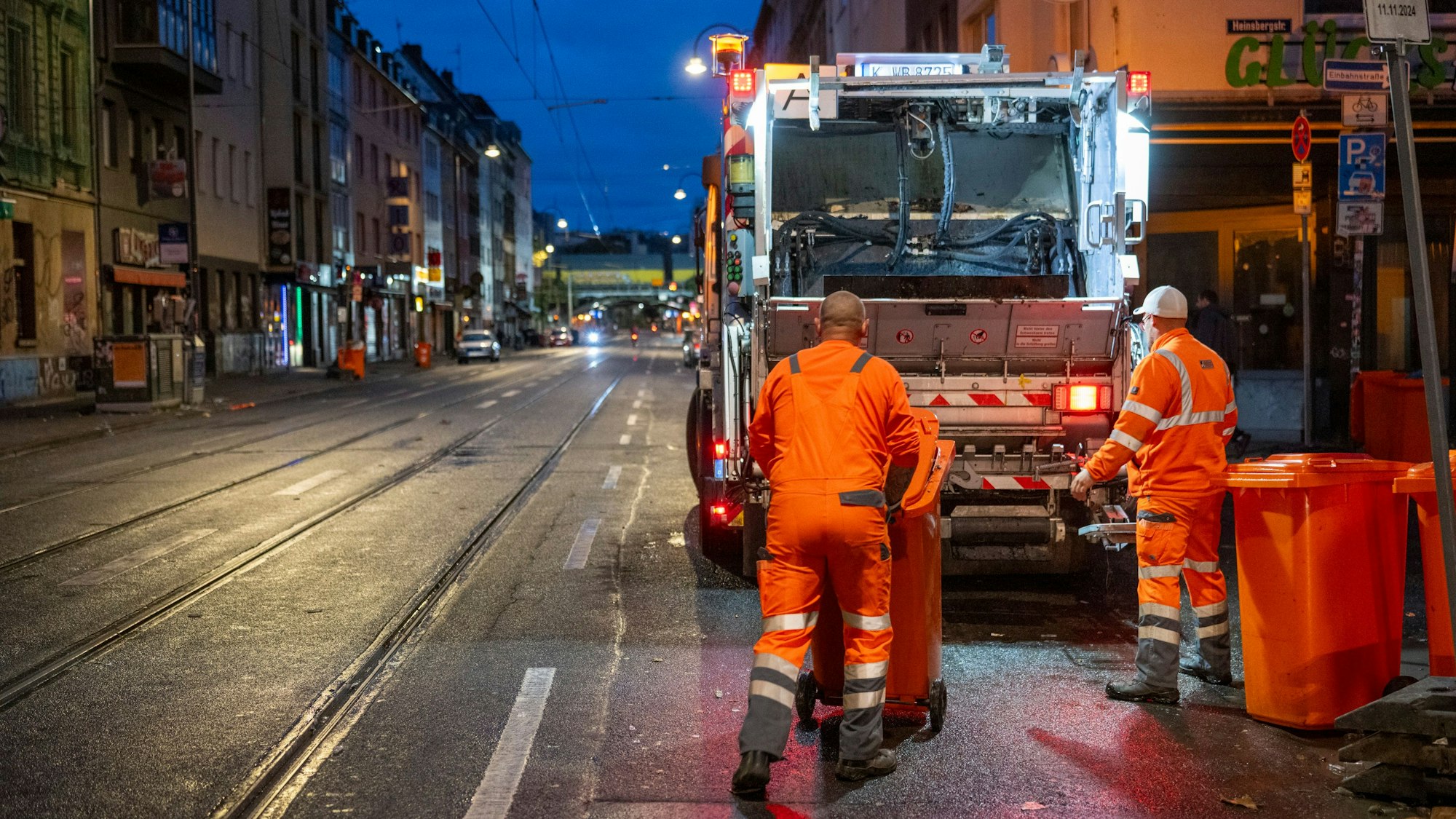Mitarbeitende der AWB leeren nach dem „Elften im Elften“ Mülltonnen, die an der Zülpicher Straße stehen.