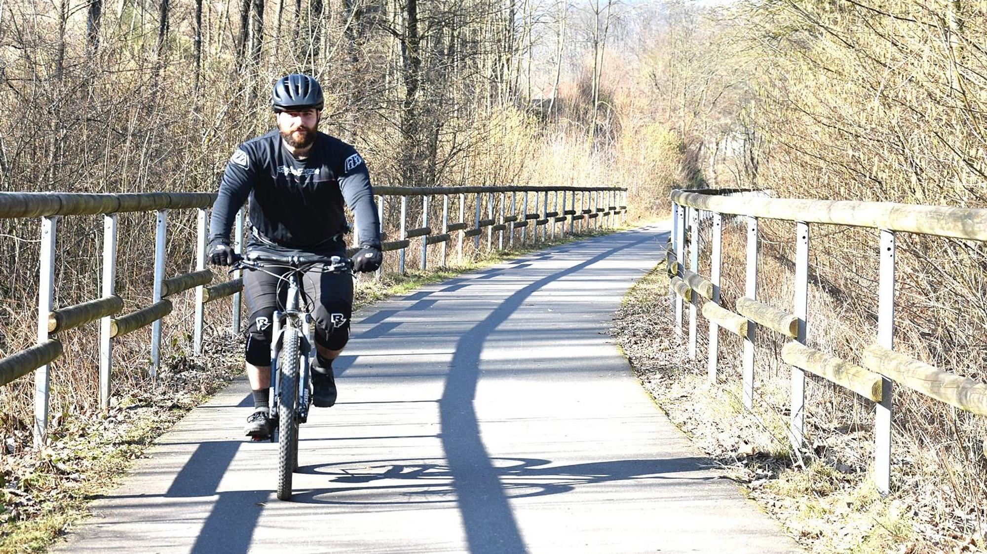 Ein Mann fährt mit einem Fahrrad auf einer alten Bahntrasse.