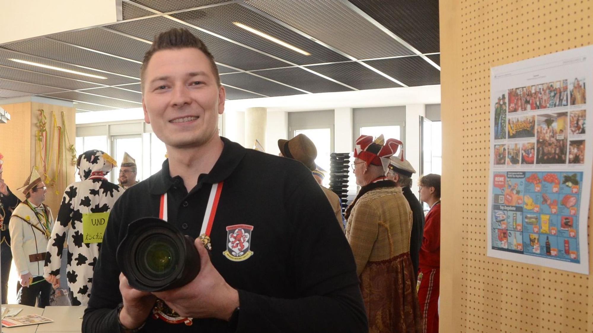 Ein Mann mit Kamera, er trägt ein schwarzes Hemd.