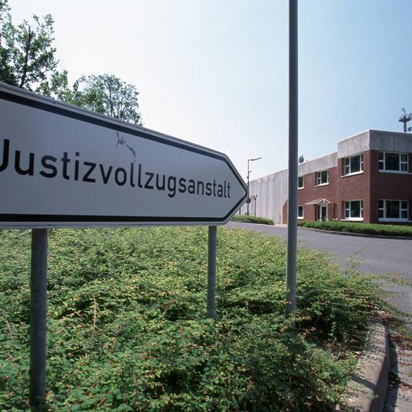 Ein Schild vor der Anstalt zeigt den Weg mit der Aufschrift Justizvollzugsanstalt.