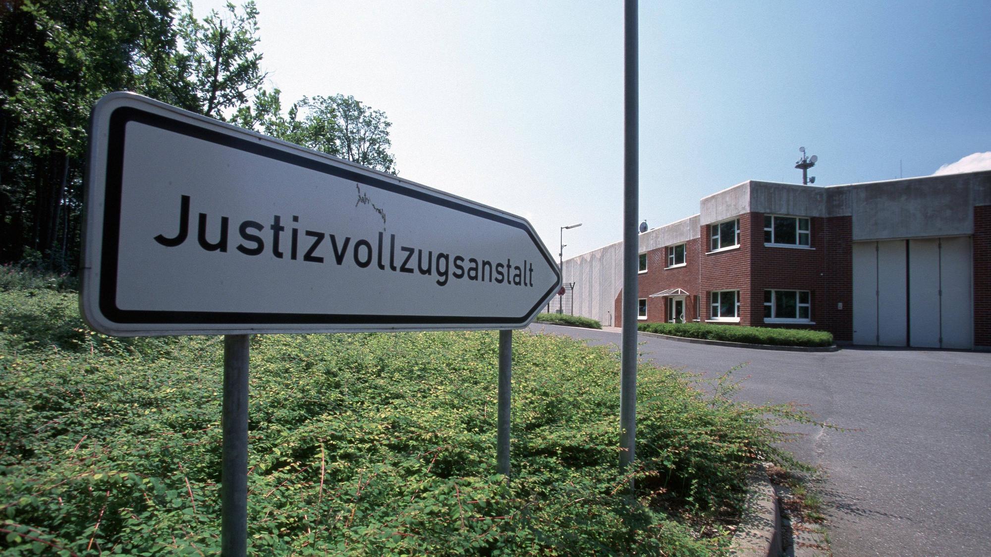 Ein Schild vor der Anstalt zeigt den Weg mit der Aufschrift Justizvollzugsanstalt.