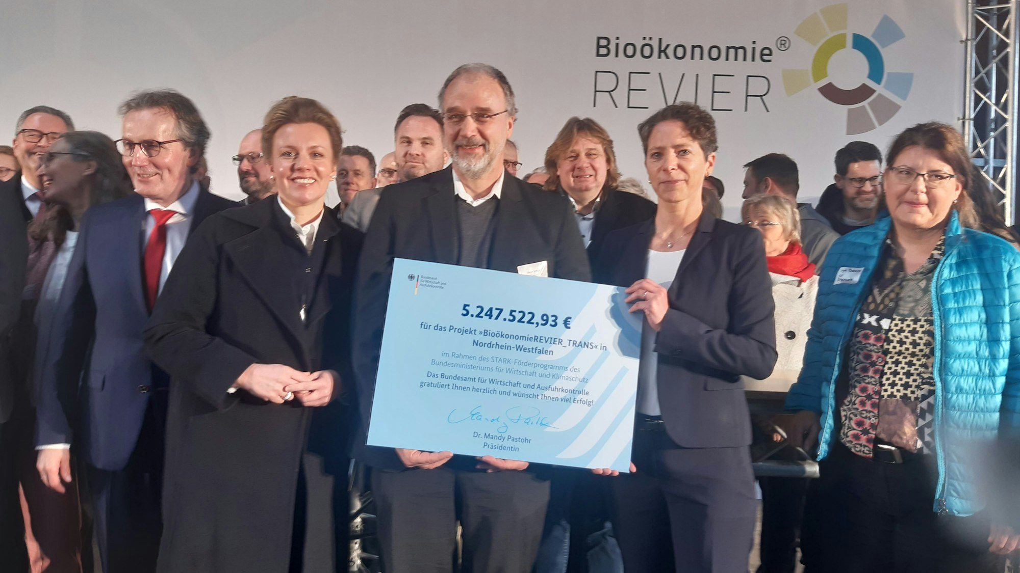 Zu sehen ist Professor Ulrich Schurr (Mitte) mit dem Förderbescheid über 5,8 Millionen Euro, den Ministerin Ina Brandes (l.) und Mandy Pastohr (r.) vom Bundesamt für Wirtschaft und Ausfuhrkontrolle überreichten.