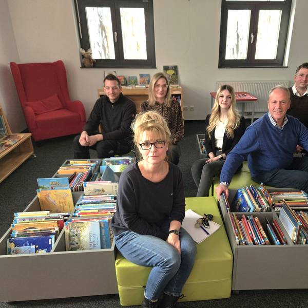 Florian Marx, Anja Schlösser, Nina Pützer, Michelle Dahm, Hermann-Josef Esser und André Kaudel sitzen auf Hockern in der Kinderbuchabteilung der Gemeindebibliothek.