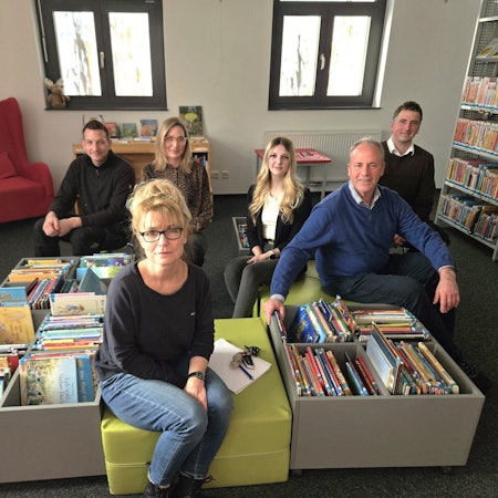 Florian Marx, Anja Schlösser, Nina Pützer, Michelle Dahm, Hermann-Josef Esser und André Kaudel sitzen auf Hockern in der Kinderbuchabteilung der Gemeindebibliothek.
