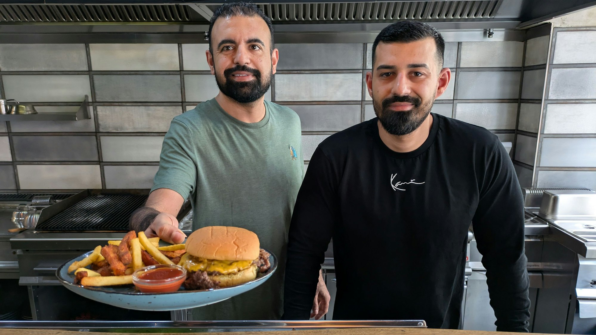 Zwei Männer stehen hinter einem Tresen und reichen Essen herüber.