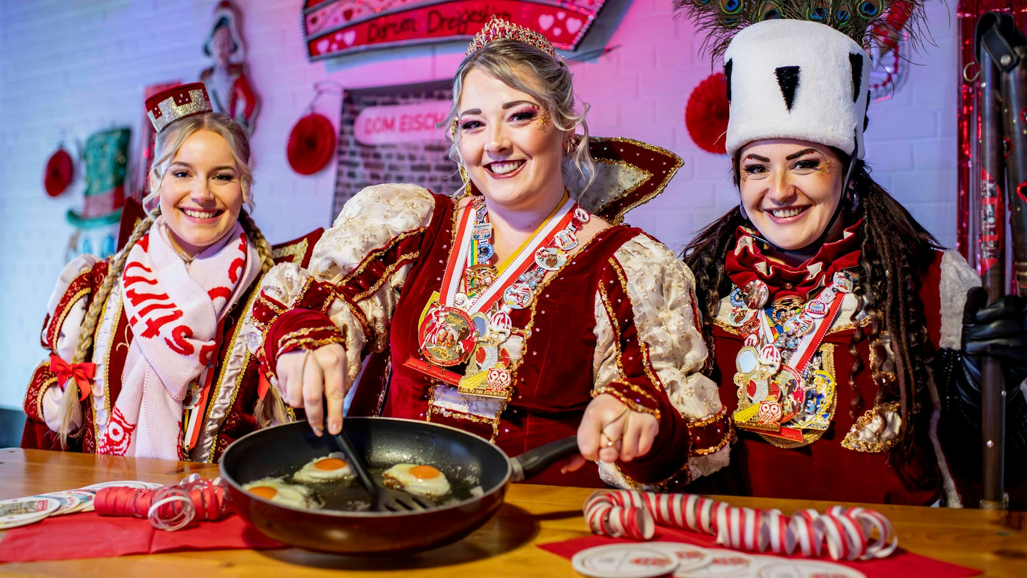 Das Bild zeigt die Tollitäten im Ornat. Prinzessin Anna hat eine Pfanne mit gebratenen Eiern in der Hand.