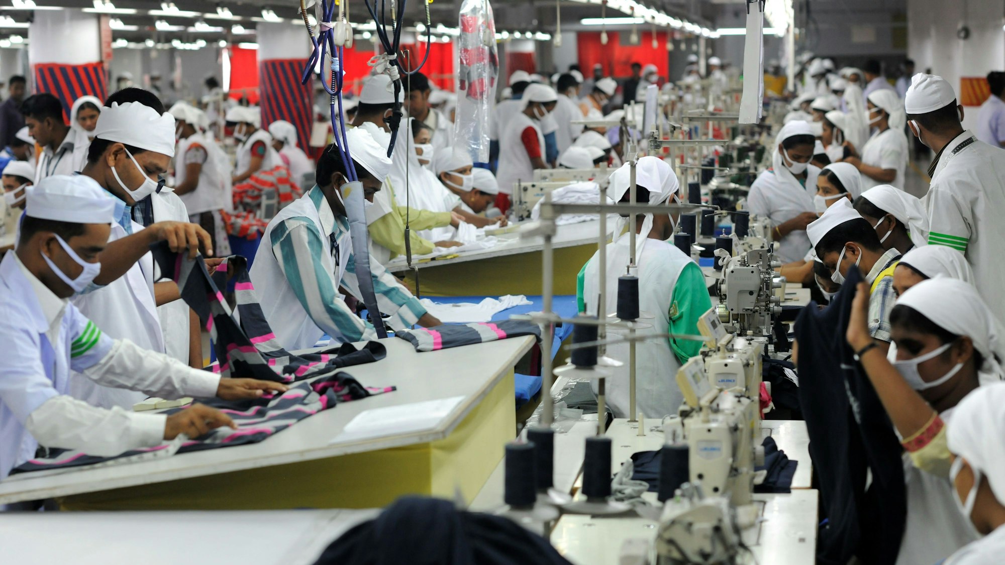 Mitarbeiter der Textilfabrik Viyellatex in einem Vorort von Dhaka arbeiten in der Produktion und nähen T-Shirts.