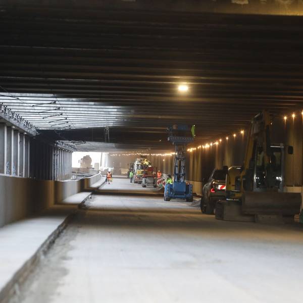 Blick in einen Tunnel, an dessen rechten Rand Baumaschinen und Fahrzeuge stehen.