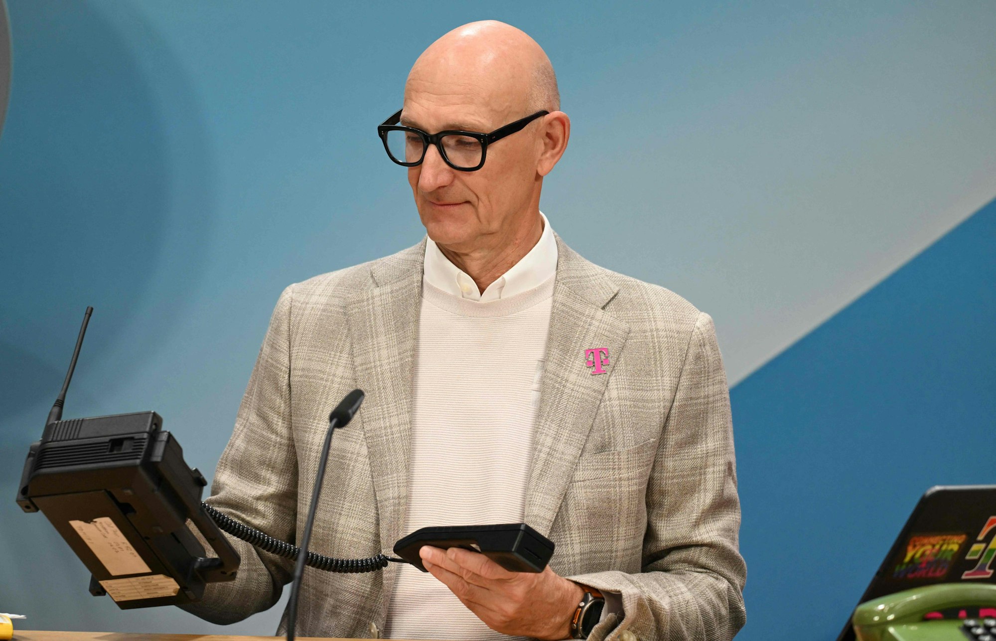 Tim Höttges hält ein Schnurtelefon aus den 90ern in der Hand.