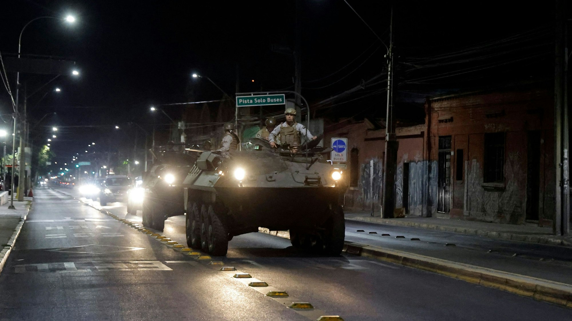 TOPSHOT - Army soldiers on a military vehicle patrol a street during a state of emergency after a blackout in Santiago on February 26, 2025. The Chilean government decreed on Tuesday a state of emergency and imposed a nighttime curfew in most of the country, including the capital Santiago, following a massive blackout caused by an alleged failure of the electrical system. (Photo by Javier TORRES / AFP)