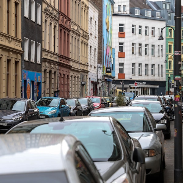 Zu sehen sind links und rechts mehrere Autos, die am Straßenrand parken.