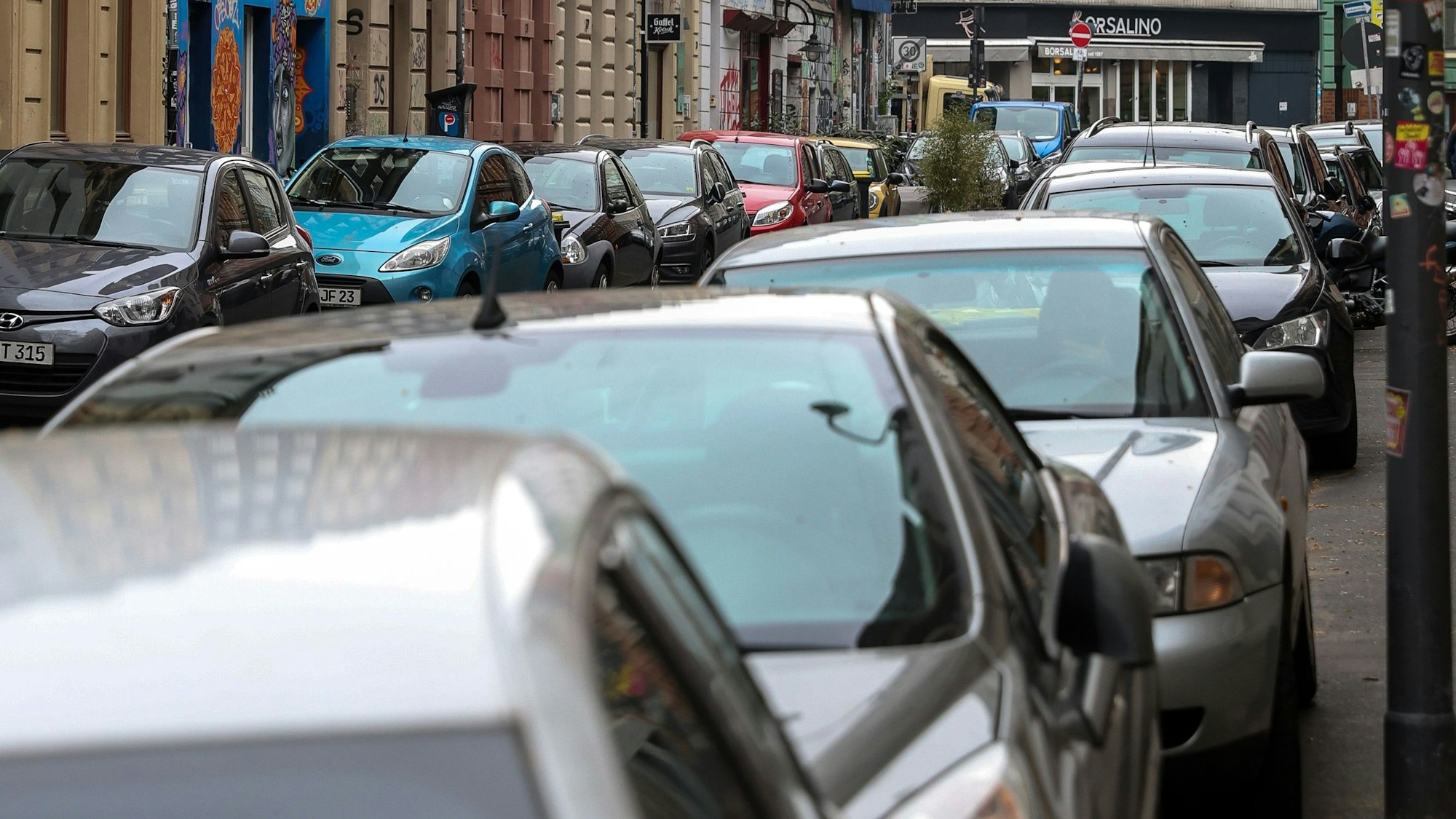 Zu sehen sind links und rechts mehrere Autos, die am Straßenrand parken.