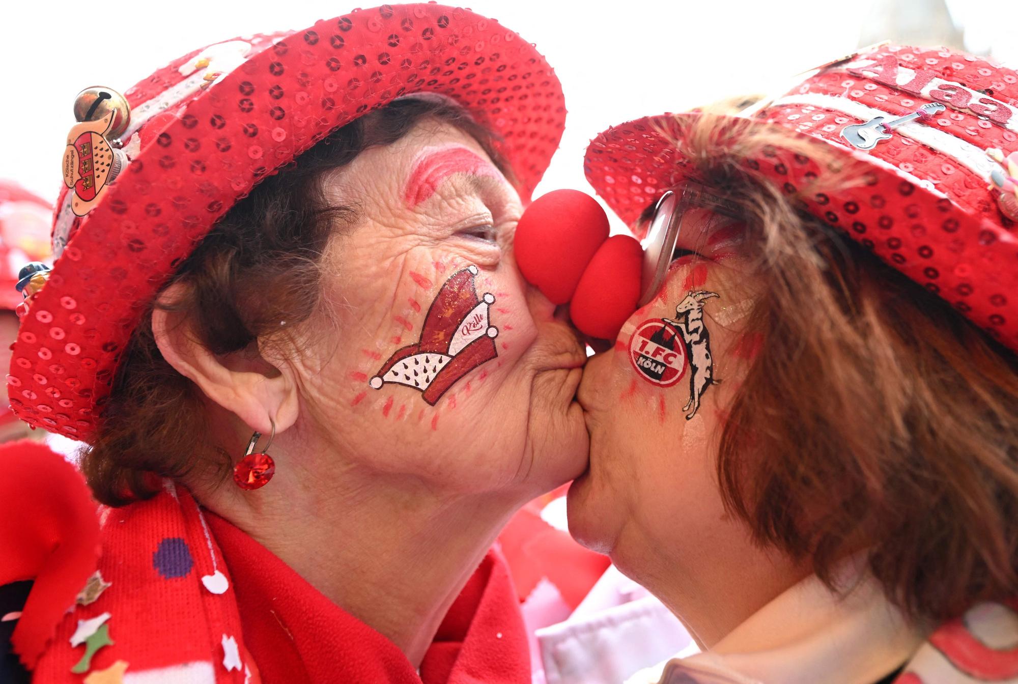 A mother and her daughter dressed as clowns kiss as carnivalists cheer during the launch of the hot carnival season in Cologne, western Germany, on February 27, 2025. (Photo by INA FASSBENDER / AFP)