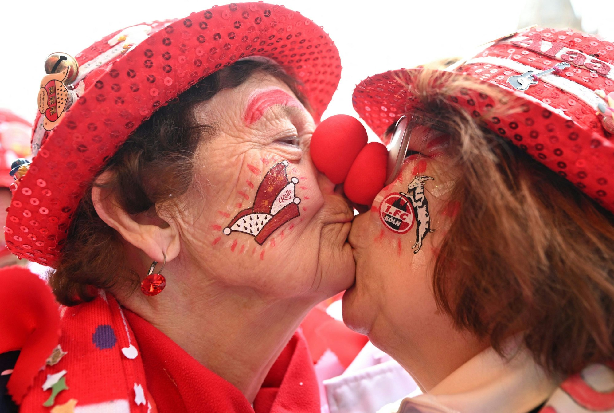 A mother and her daughter dressed as clowns kiss as carnivalists cheer during the launch of the hot carnival season in Cologne, western Germany, on February 27, 2025. (Photo by INA FASSBENDER / AFP)