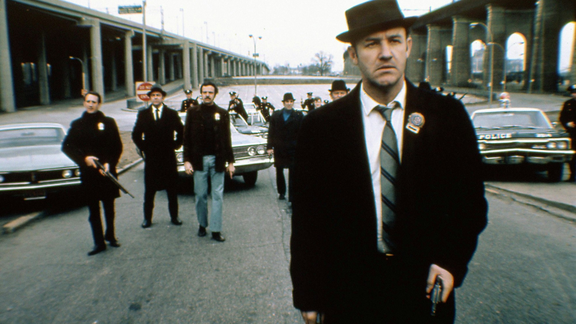 Ein Polizist steht mit Waffe in der Hand auf einer Straße.