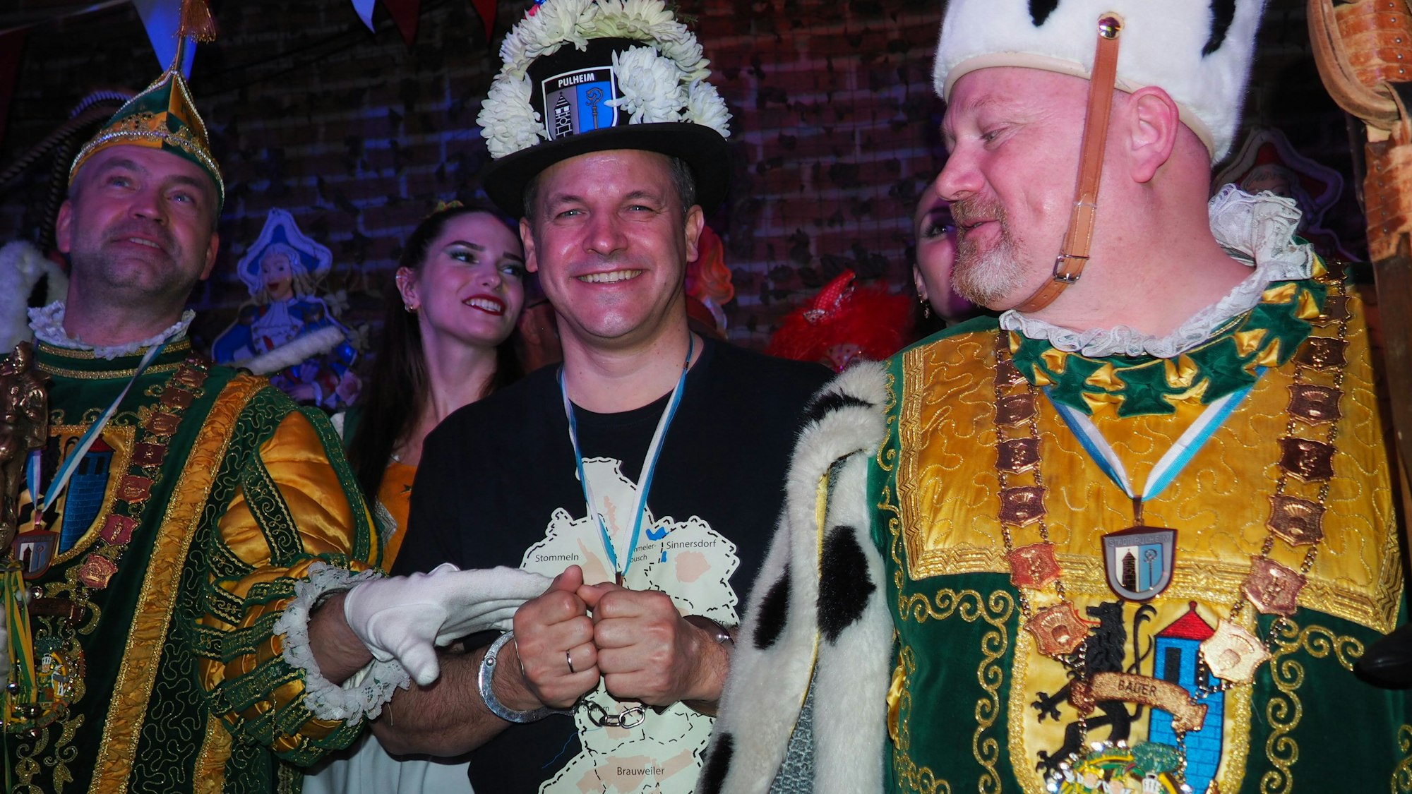 Ein Mann in Handschellen, er trägt einen mit weißen Blumen geschmückten Hut.