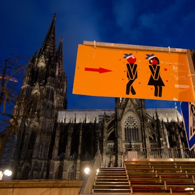 Ein Schild vor dem Dom weist den Weg zu den Toiletten für die feiernde Karnevalisten.