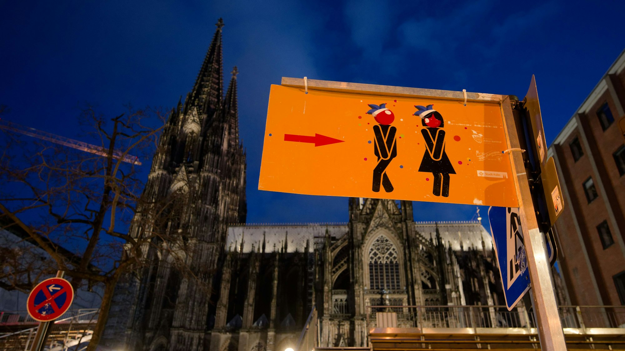 Ein Schild vor dem Dom weist den Weg zu den Toiletten für die feiernde Karnevalisten.