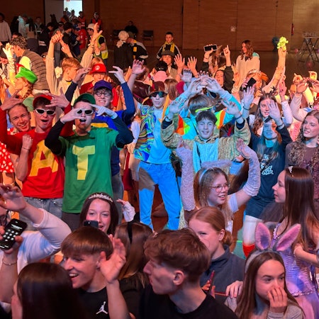 Eine jugendliche Menge hebt die Arme in einem Saal.