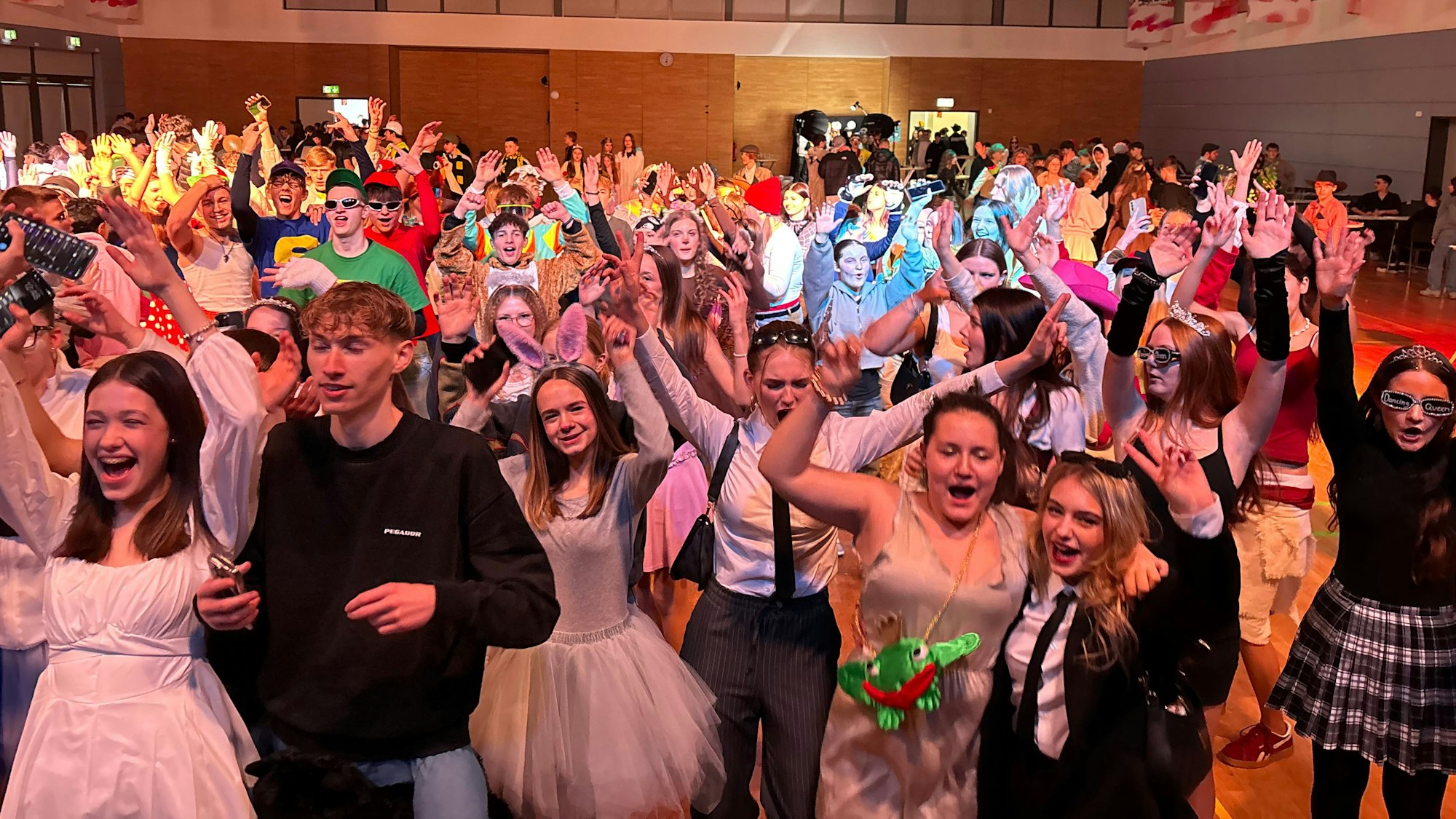 Eine Masse Jugendlicher steht in einer Halle und feiert.