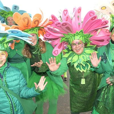 Eine Gruppe als Blumen verkleideter Jecken winkt in die Kamera.