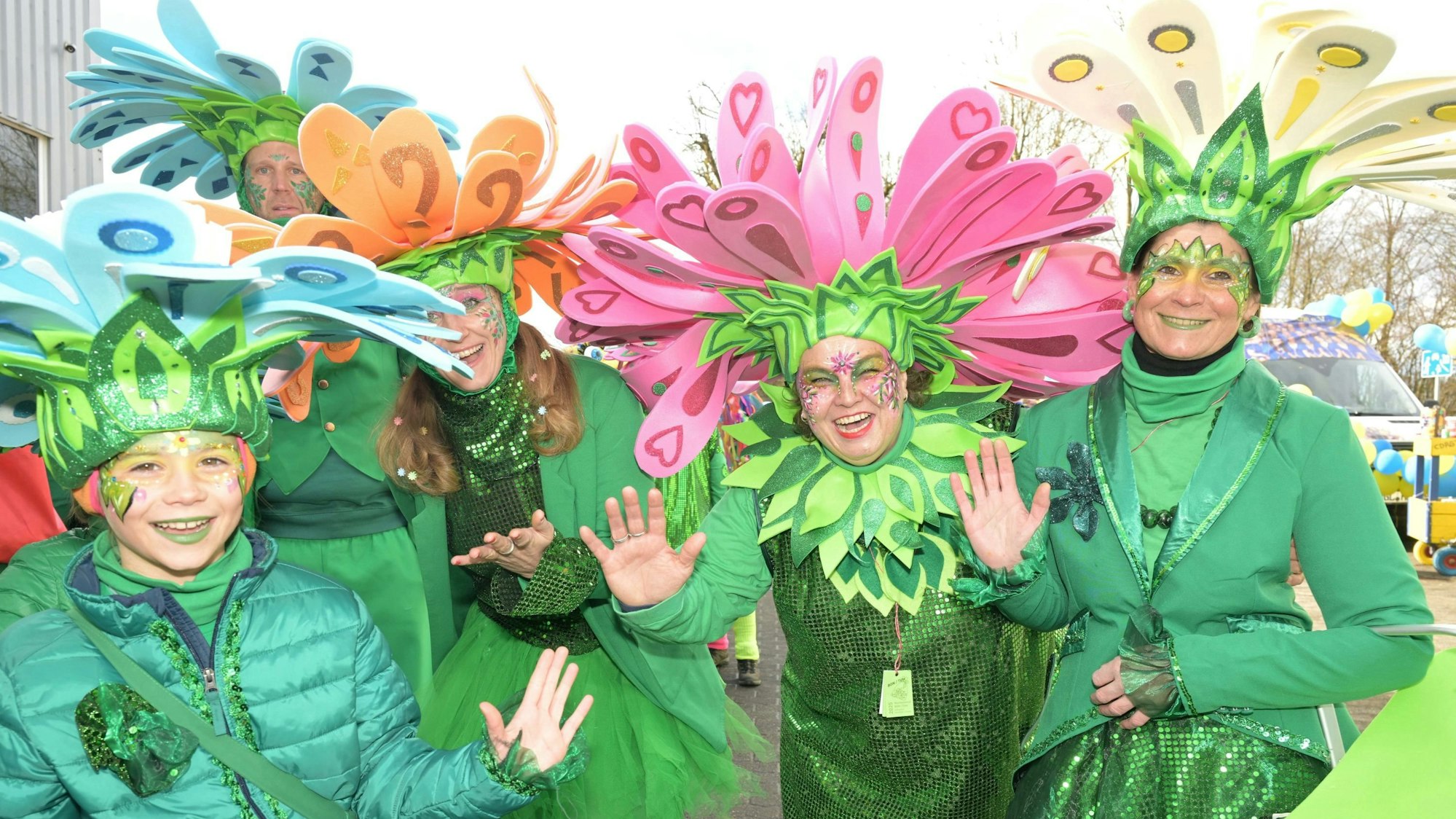 Eine Gruppe als Blumen verkleideter Jecken winkt in die Kamera.
