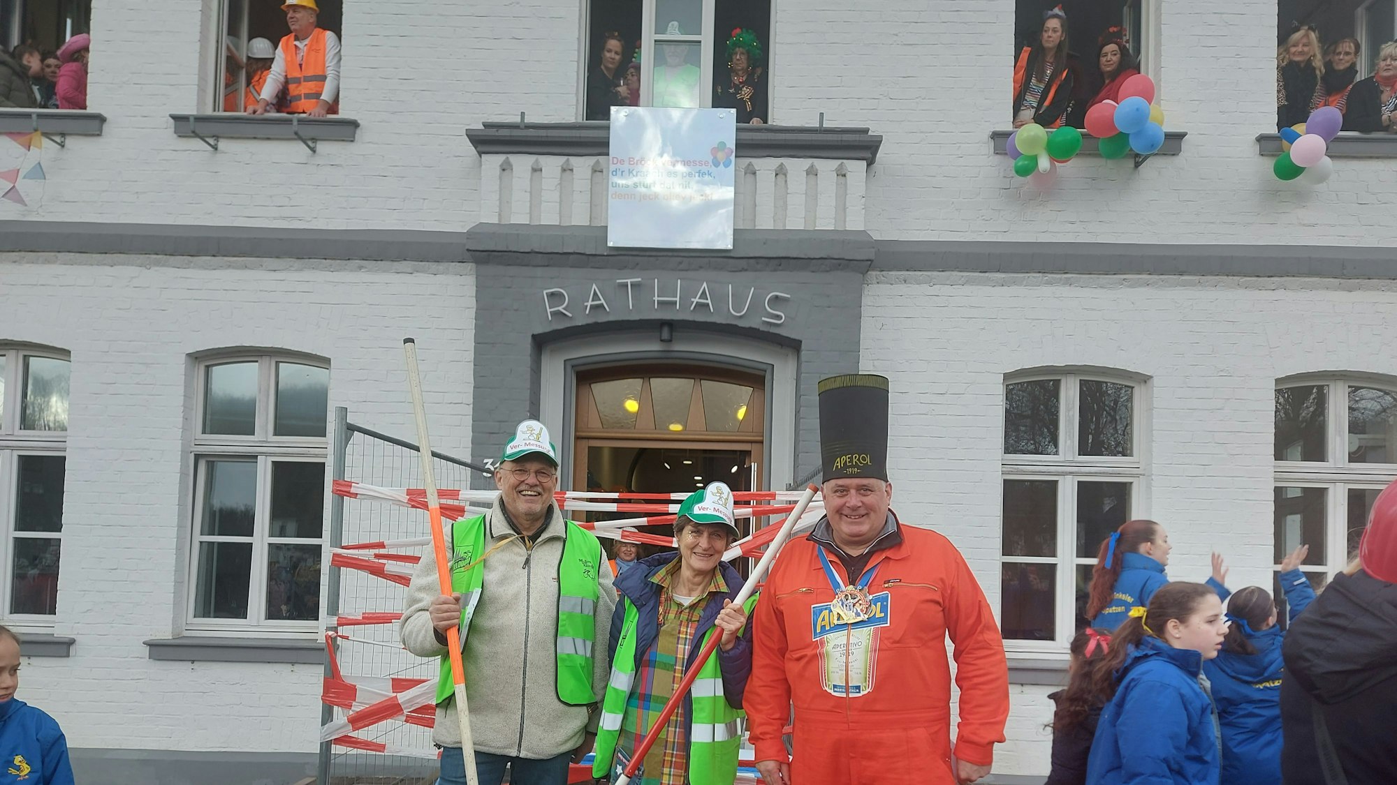 Drei Menschen stehen vor einem Rathaus.