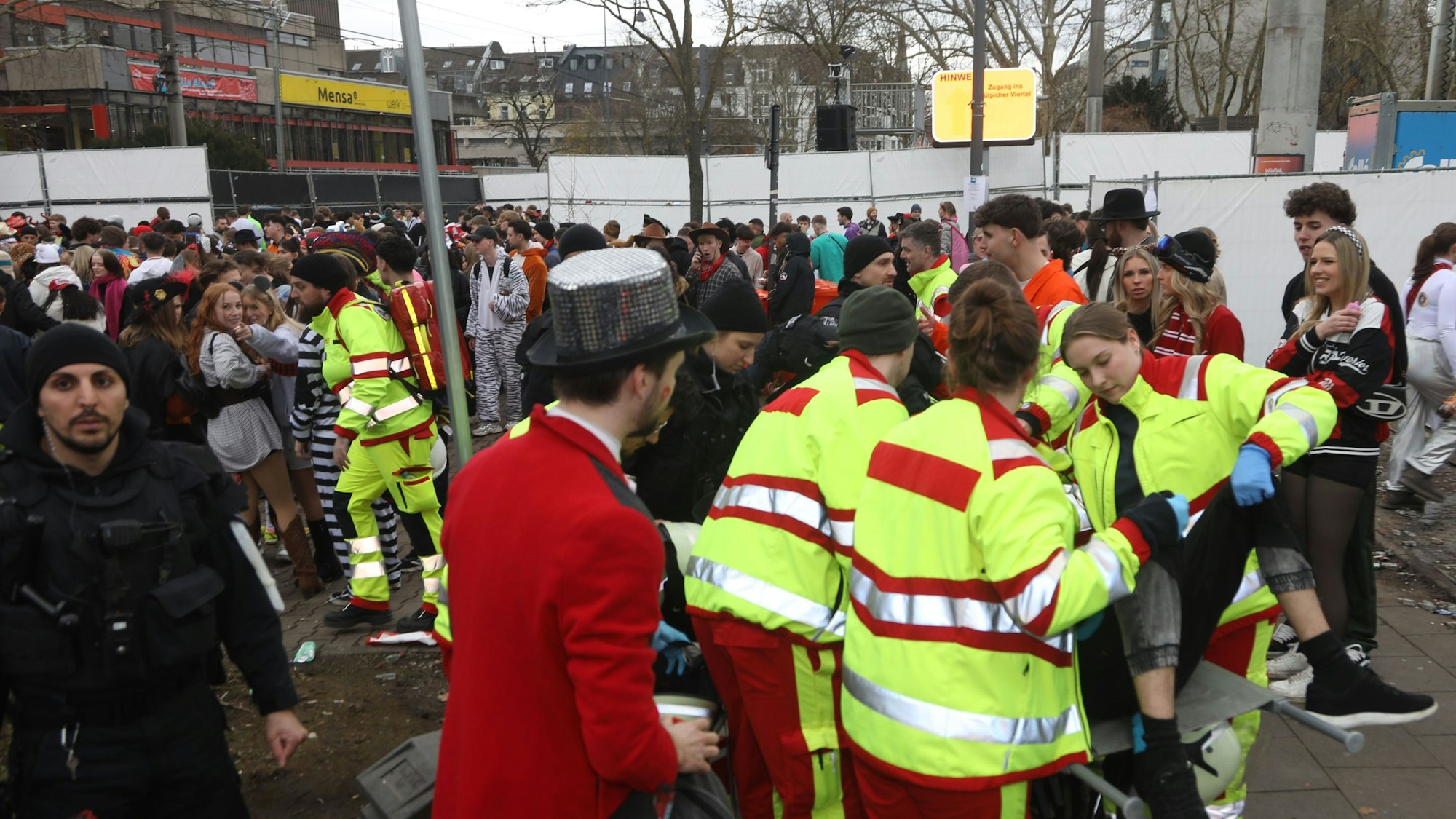 Ein Jeck wird vom Rettungsdienst an der Zülpicher Straße abtransportiert, er ist nicht der Einzige, der an Weiberfastnacht auf die Hilfe der Sanitäter angewiesen ist.