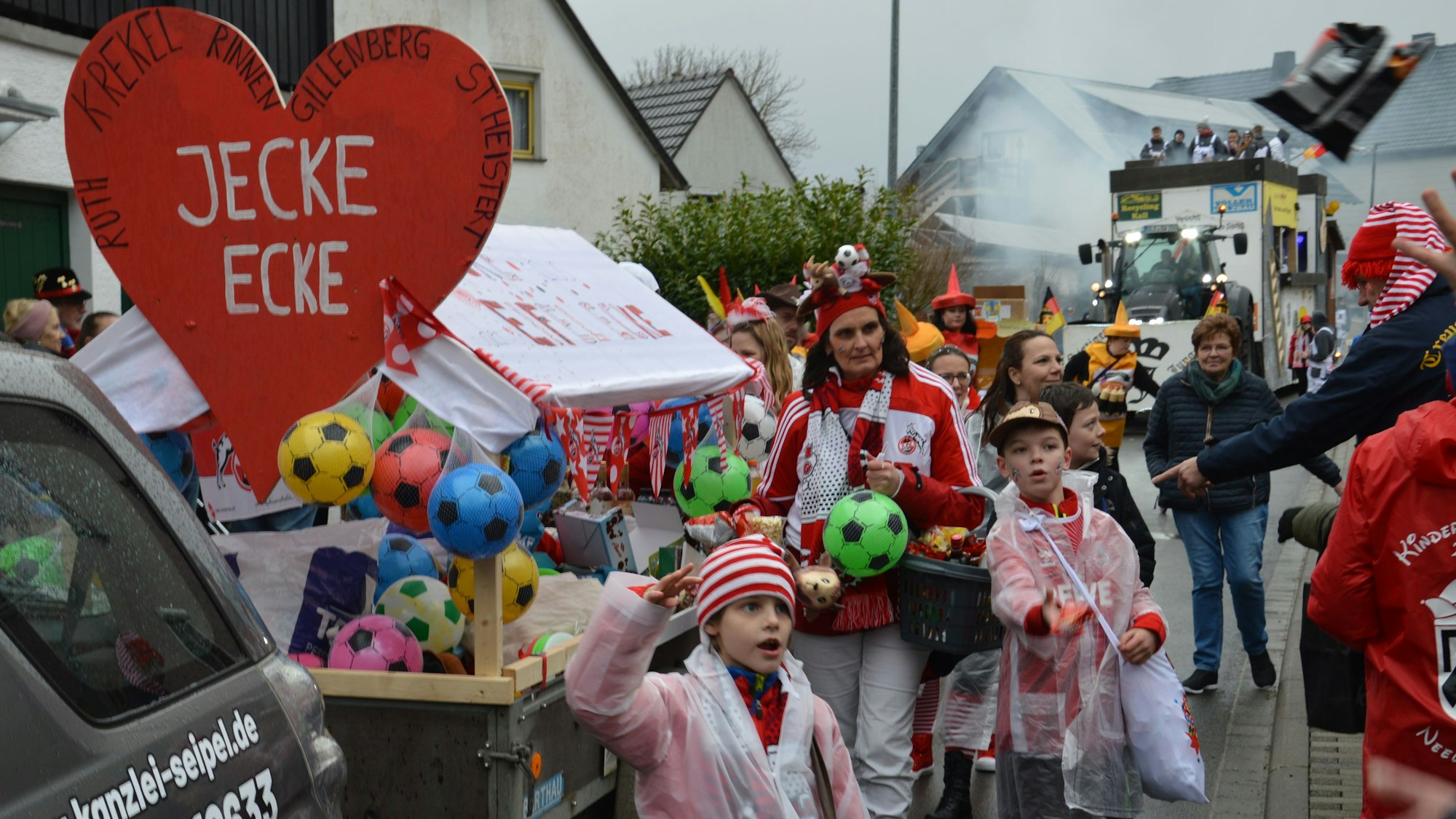 Zahlreiche kostümierte Karnevalisten beteiligen sich am Zug in Kall-Wahlen. Auf einem Anhänger haben sie ein rotes Herz mit der Aufschrift „jecke Ecke“ befestigt.