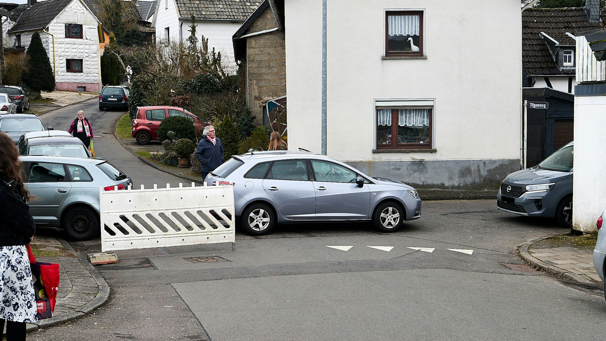 Auf einer Straßenkreuzung stehen ein Bauzaun und ein Auto.
