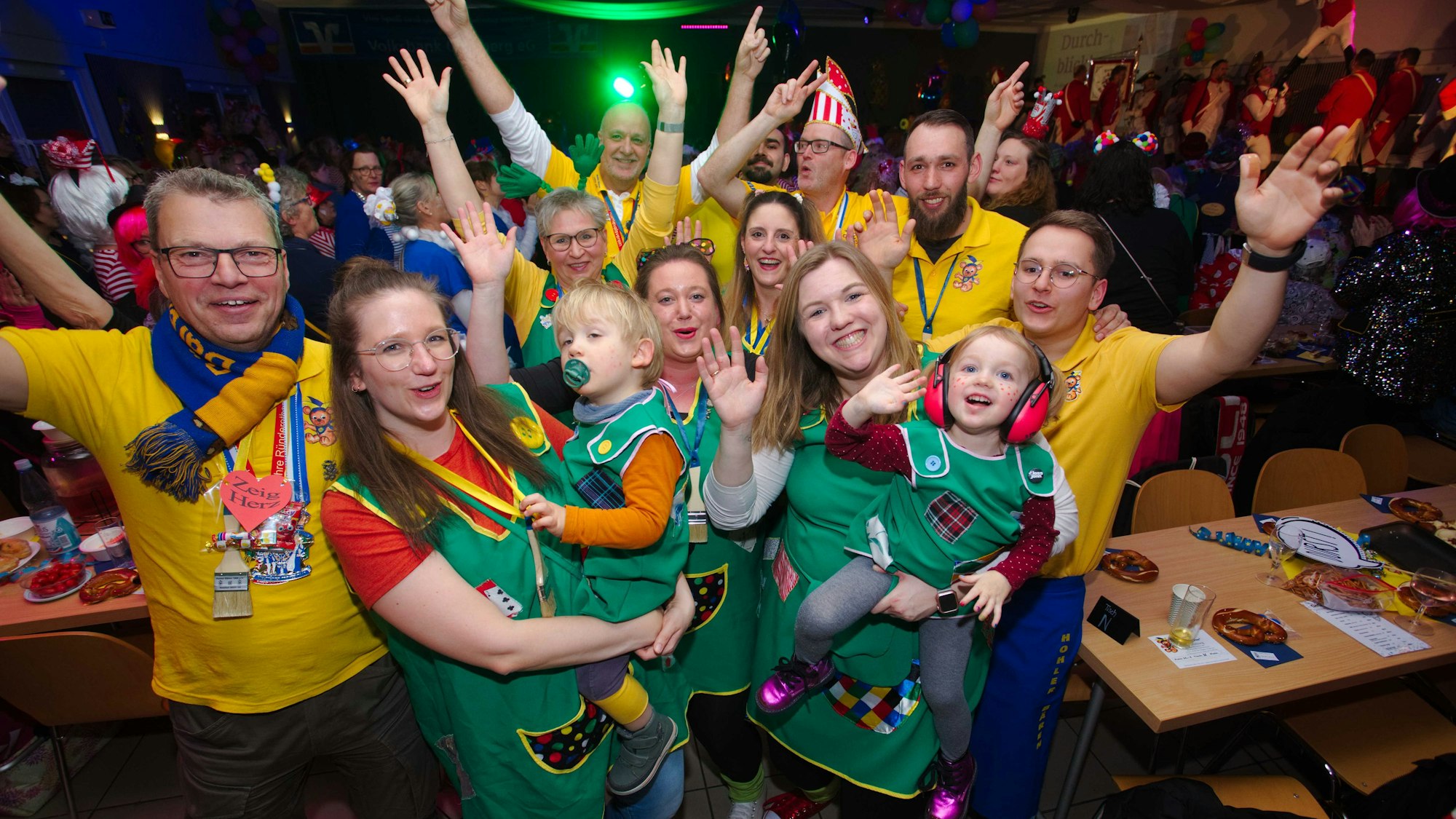 Eine Gruppe in einem gemeinsamen Gruppenkostüm jubelt bei einer Karnevalssitzung in die Kamera.