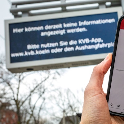 12.02.2025, Köln: Eine Fehlermeldung in der App der Kölner Verkehrsbetriebe (KVB) auf dem Display eines Smartphones sowie eine Störungsmeldung auf einer Anzeige zur Fahrgastinformation sind an einer Haltestelle zu sehen. Umfassende und mehrere Stunden andauernde Probleme beim Internetprovider NetCologne haben zu grossflächigen Störungen geführt. Foto: Matthias Heinekamp