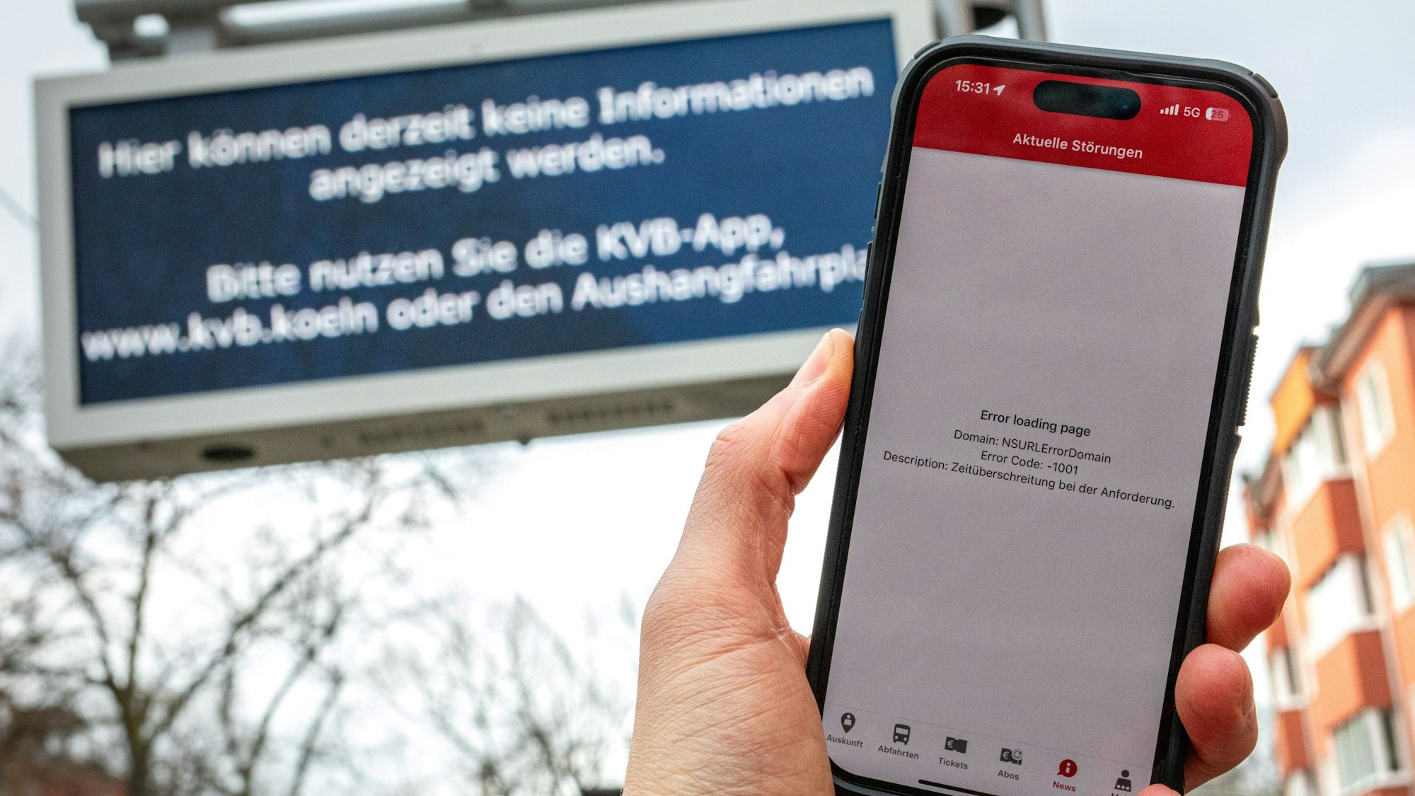 12.02.2025, Köln: Eine Fehlermeldung in der App der Kölner Verkehrsbetriebe (KVB) auf dem Display eines Smartphones sowie eine Störungsmeldung auf einer Anzeige zur Fahrgastinformation sind an einer Haltestelle zu sehen. Umfassende und mehrere Stunden andauernde Probleme beim Internetprovider NetCologne haben zu grossflächigen Störungen geführt. Foto: Matthias Heinekamp