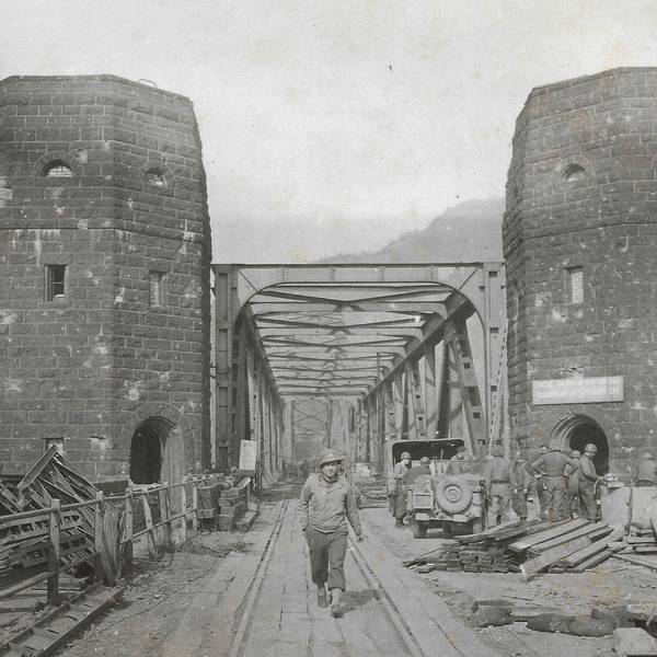 Eine historische Aufnahme, auf der ein Soldat zwischen den Türmen der Brücke von Remagen hindurch geht.