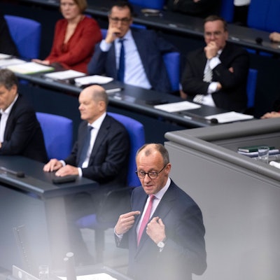 Das Bild zeigt Friedrich Merz (CDU), der wahrscheinlich kommende Bundeskanzler (vorne) und seinen Vorgänger Olaf Scholz (SPD, zweite Reihe rechts) bei einer Debatte im Bundestag.