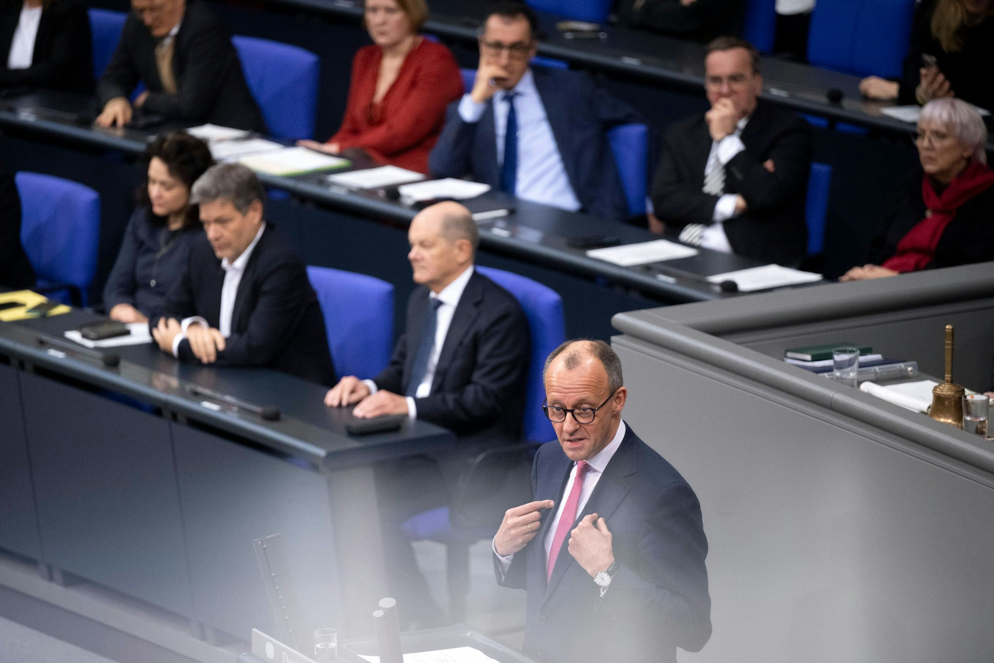 Das Bild zeigt Friedrich Merz (CDU), der wahrscheinlich kommende Bundeskanzler (vorne) und seinen Vorgänger Olaf Scholz (SPD, zweite Reihe rechts) bei einer Debatte im Bundestag.