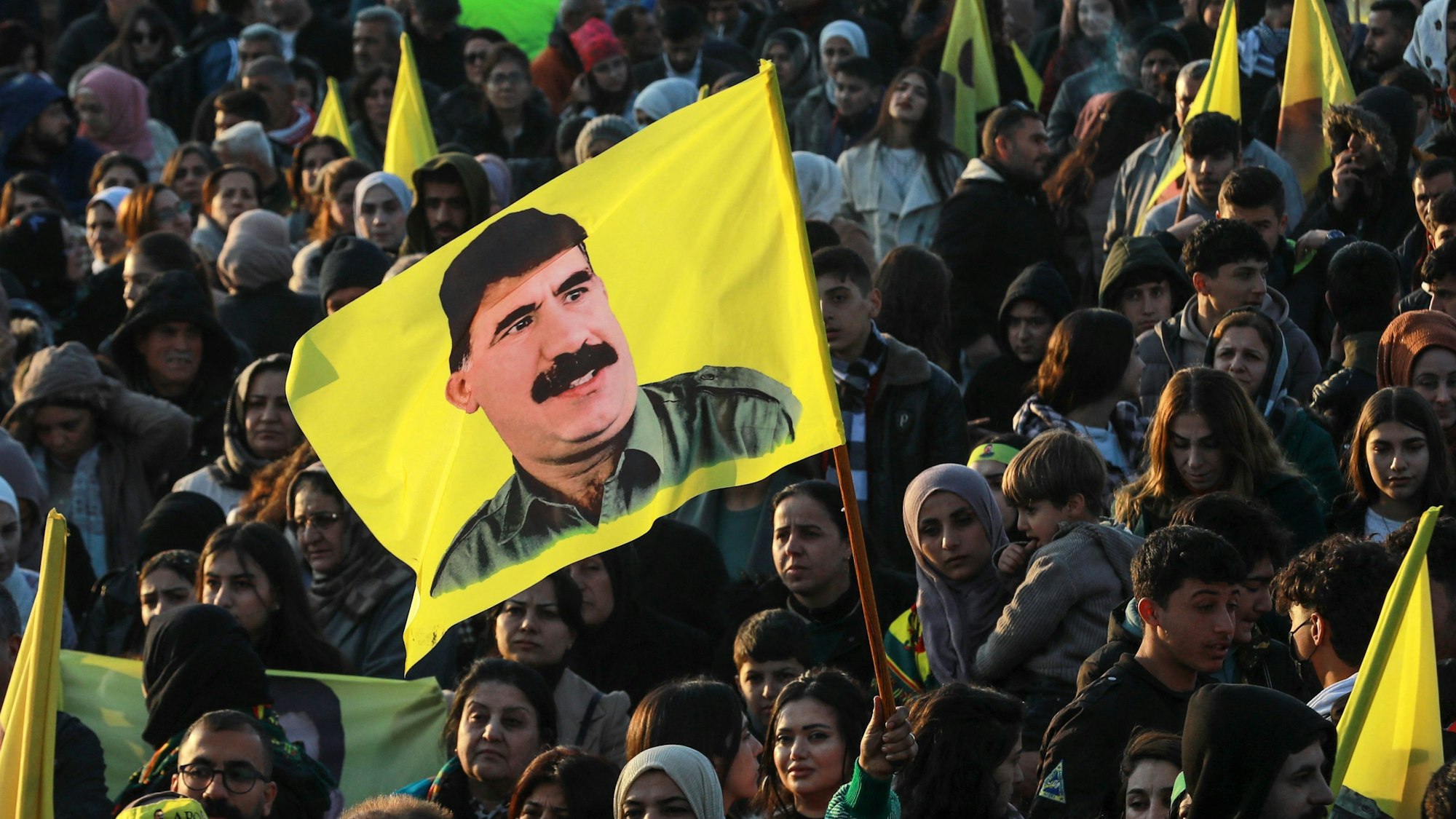 Auf dem Foto ist eine Frau zu sehen, die bei einer Demonstration eine Flagge des Gründers und Anführers der verbotenen türkischen Arbeiterpartei PKK, Abdullah Öcalan, schwenkt.