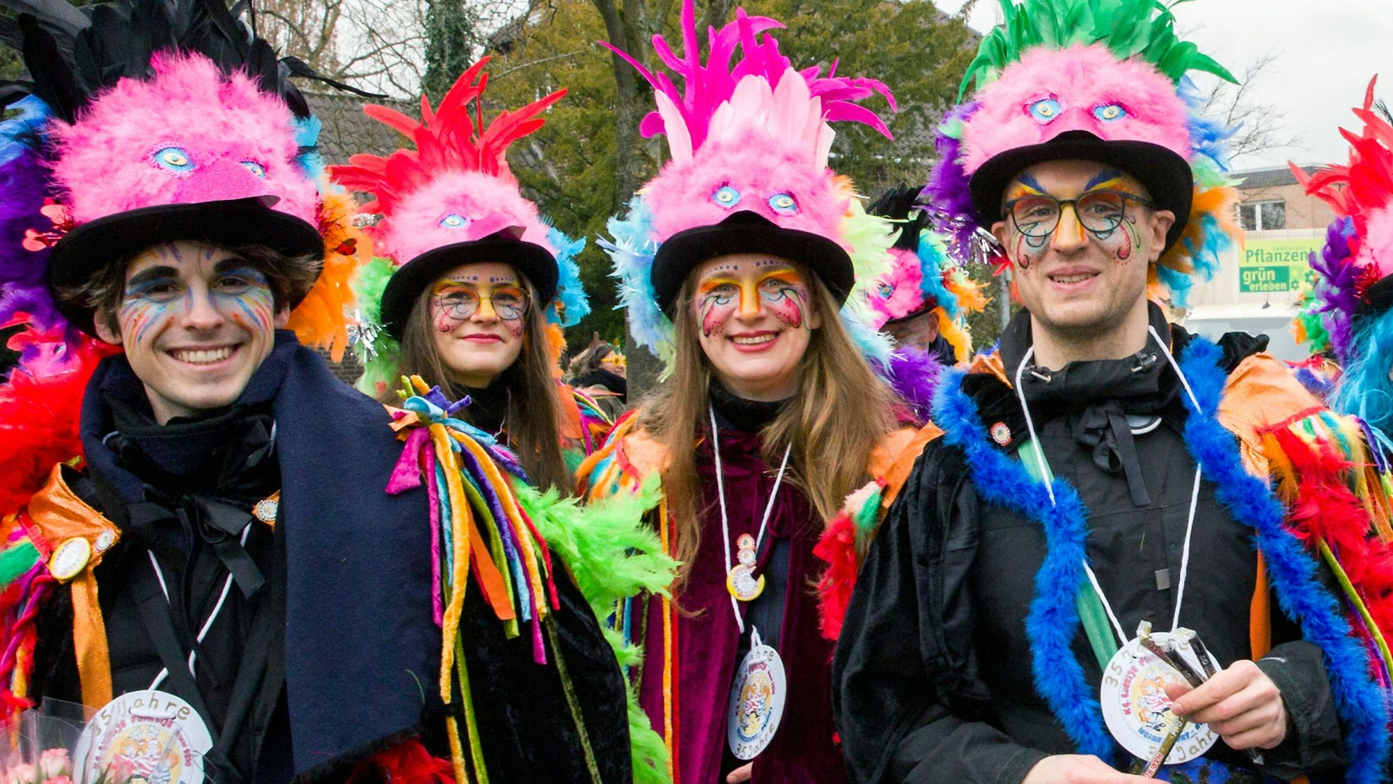 Vier junge Leute in bunten Kostümen lachen in die Kamera.