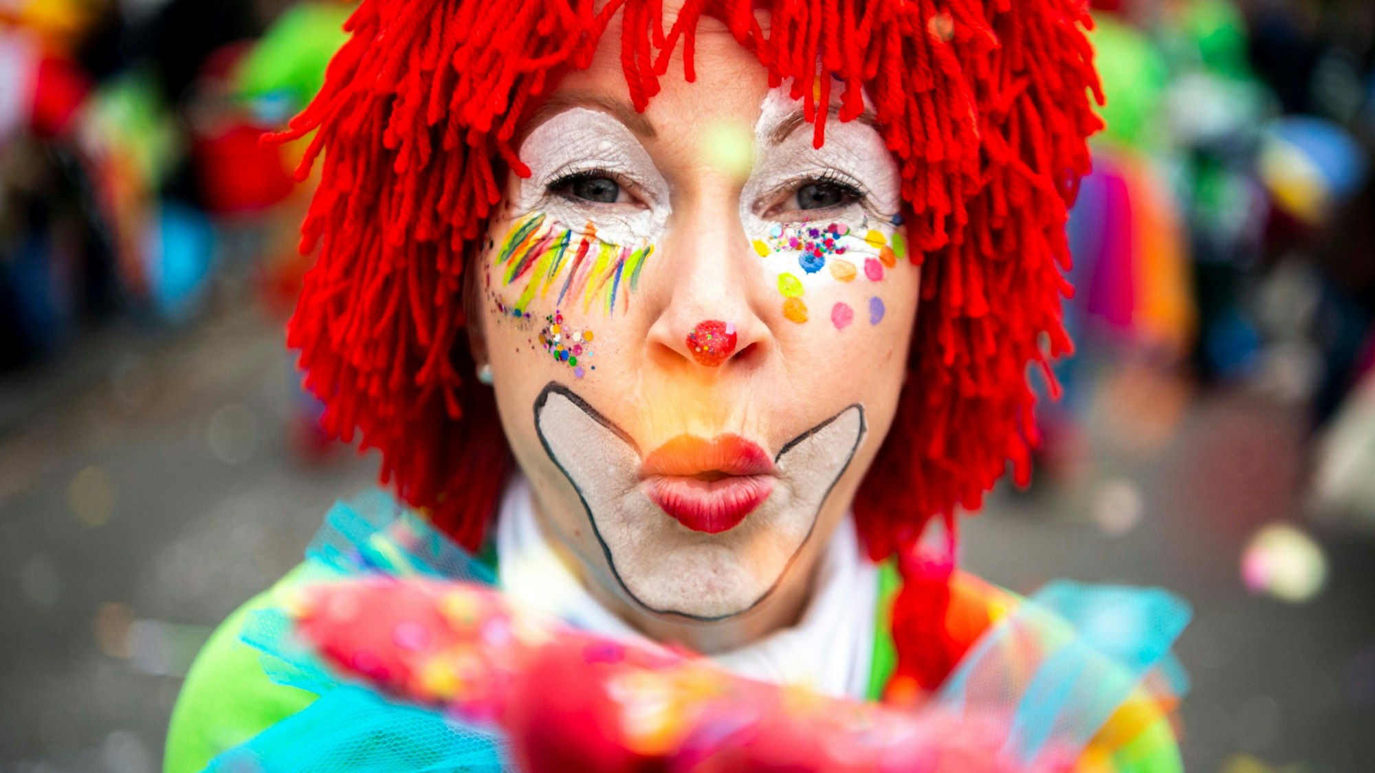 Das Bild zeigt einen Clown, der Konfetti in die Luft pustet.