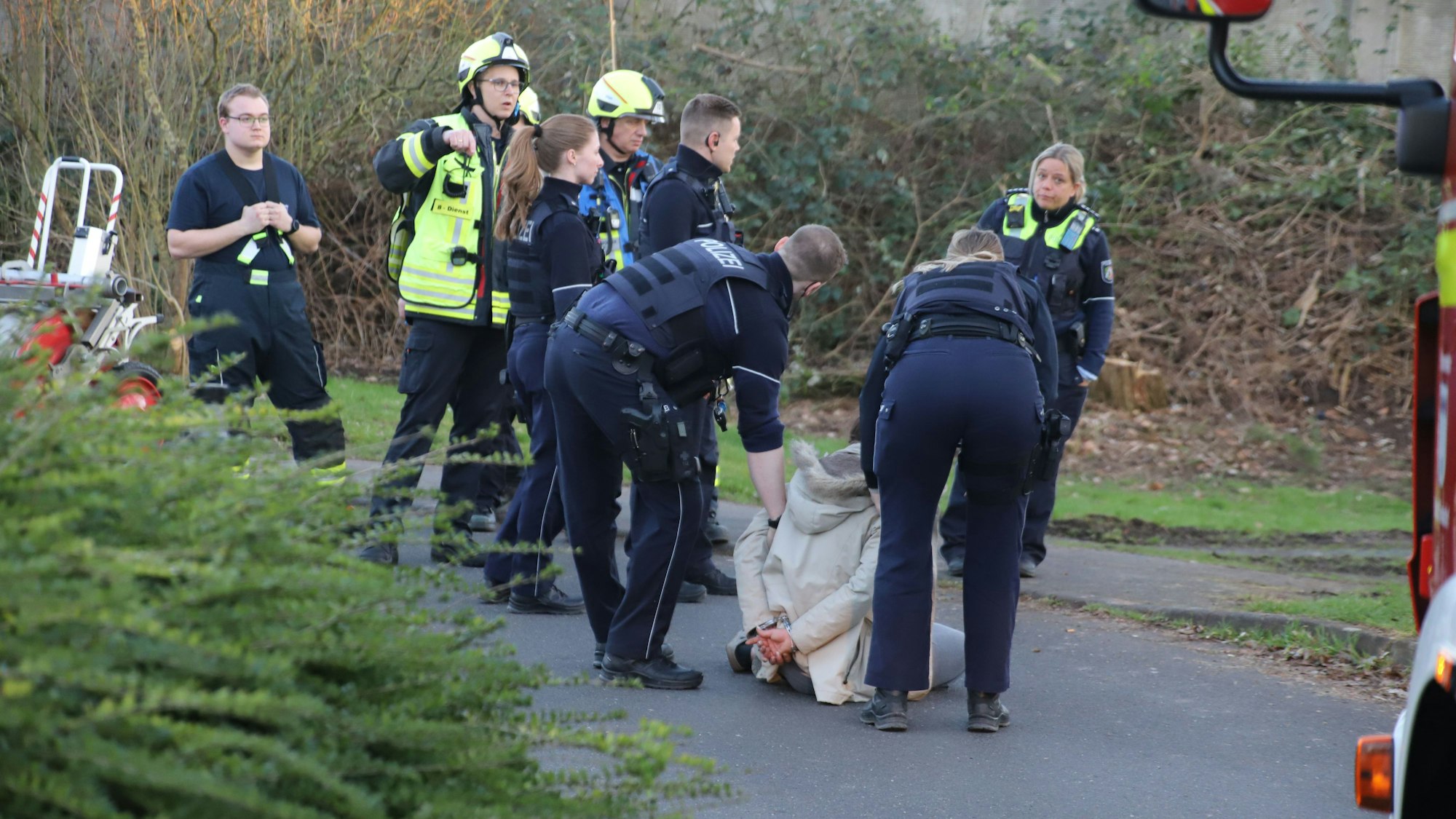 Polizisten halten eine Frau fest, die sich auf den Boden geworfen hat.