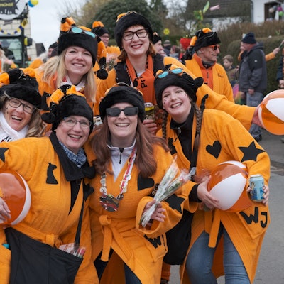 Die Karnevalsgruppe „Wilde Jecken“ aus Oberodenthal lachen im orangefarbenen Kostüm in die Kamera.
