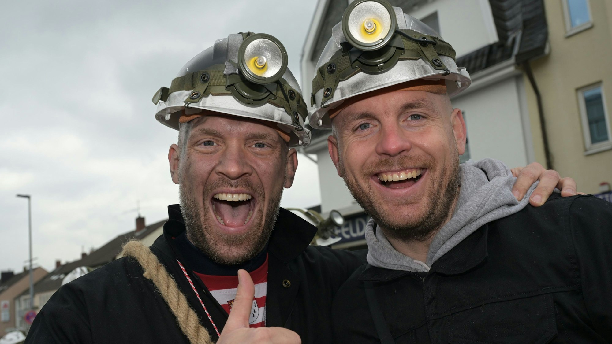 Menschen mit Bergbauhelmen gehen im Zug mit und schwenken Blumen.