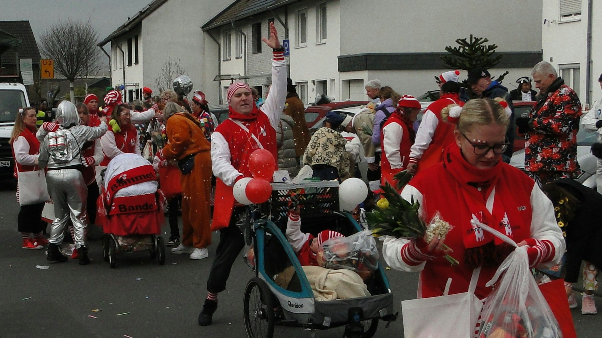 Rot-weiß gekleidete Jecke ziehen durch die Straßen von Merkenich.