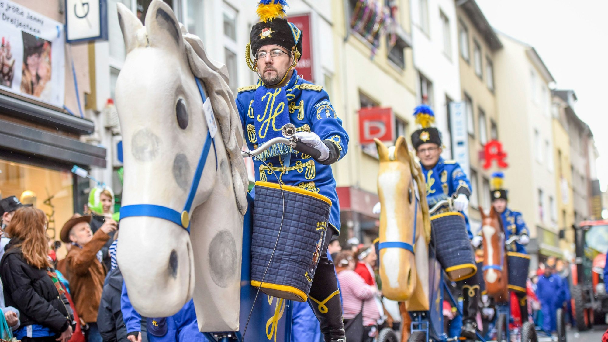 04.03.2019, Köln: Mitglieder der KG Treuer Husar Blau-Gelb von 1925 e.V. Köln nehmen auf pedalgetriebenen Gestellen mit einem Pferdekopf an Rosenmontagszug teil. Aufgrund der Gefahr von Sturmböen dürfen keine Pferde am Zug teilnehmen. Foto: Uwe Weiser (Stringer) - Karneval, Karnevalszug, Karneval, Brauchtum, Rosenmontag *bestpix*