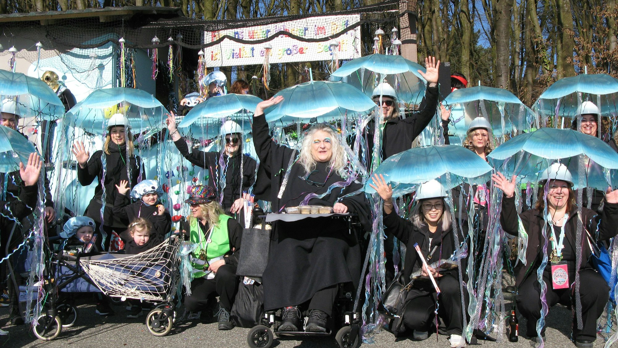 Eine Gruppe von Frauen, die mit blauen Schirmen auf dem Kopf Quallen darstellen.
