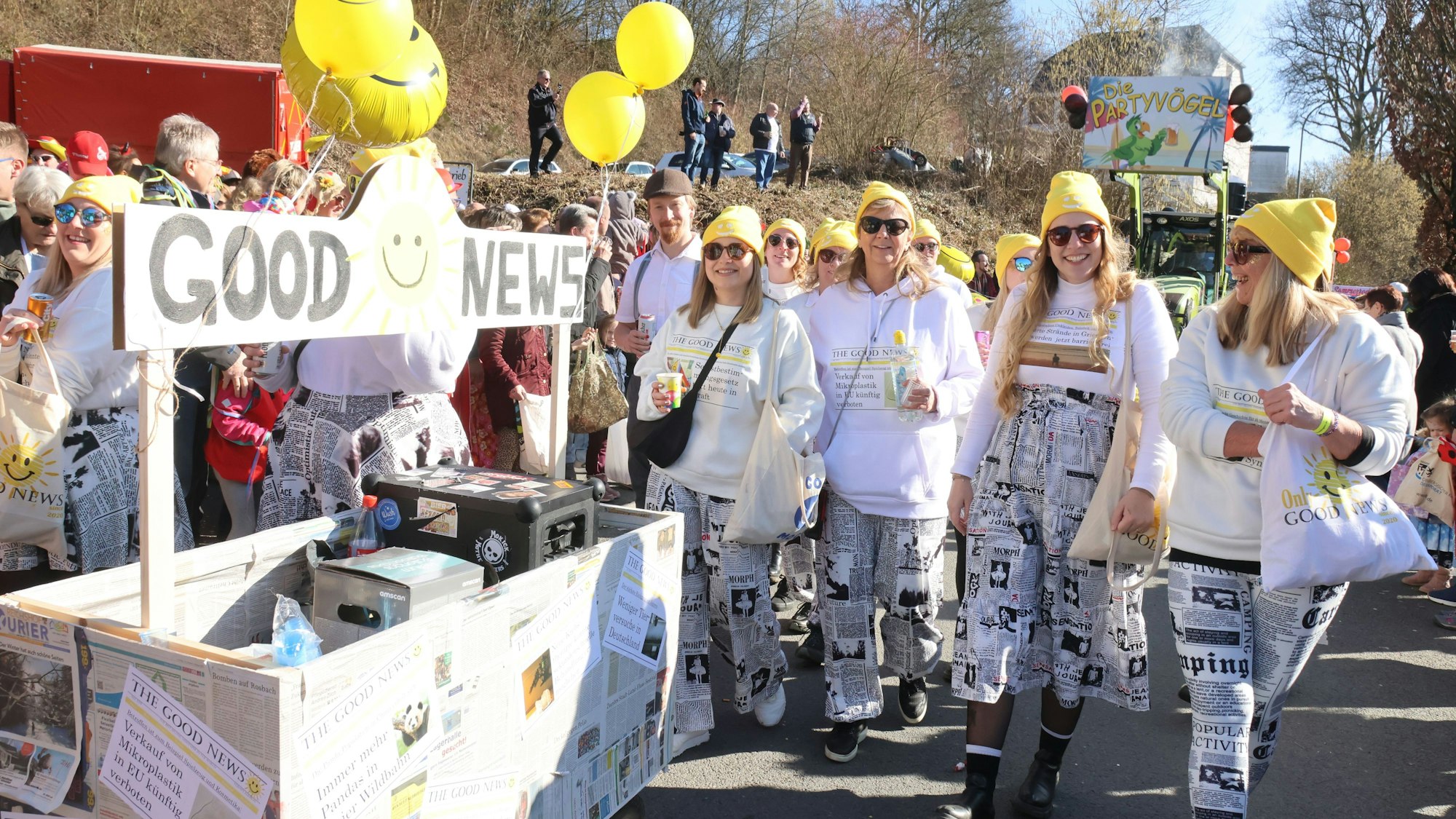 Eine als Zeitungen verkleidete Gruppe in einem Karnevalszug. Das Motto des Wagens: „Good News“.